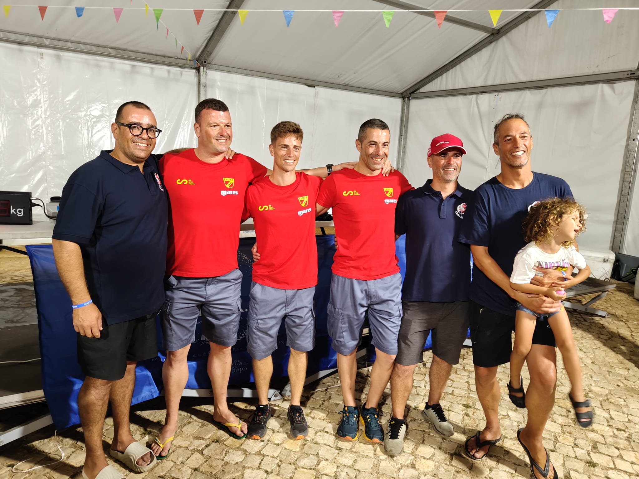 Spanish spearfishing team members in red FEDAS shirts posing with other attendees at the 2026 World Cup in Sagres