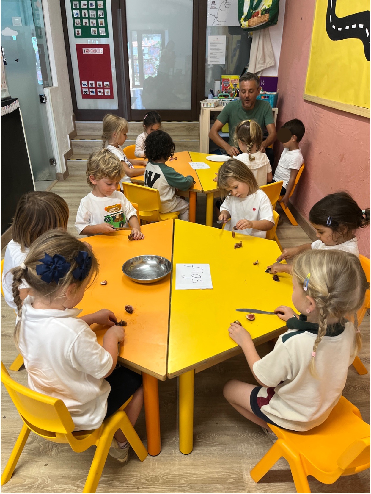 Early Years pupils preparing figs around classroom tables with their teacher