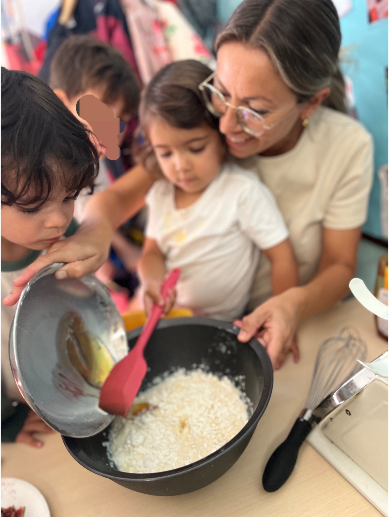 A teacher supporting Early Years pupils as they add ingredients to a bowl