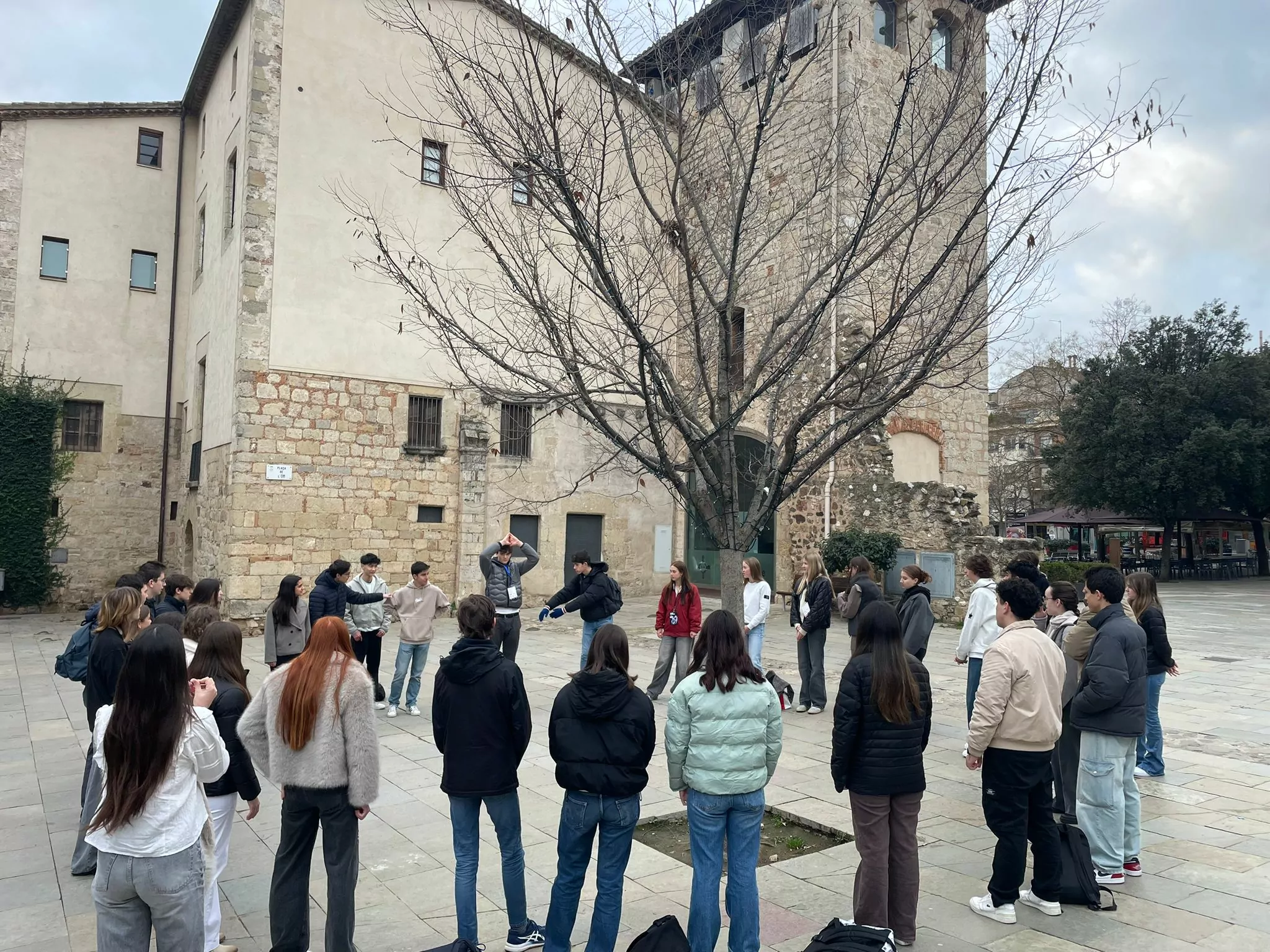 A group of young students forming a circle, actively participating in a game during their time at the European Youth Parliament, engaging in teamwork and fun